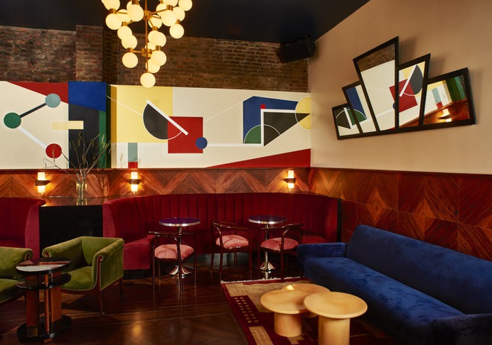 A mural by Argentinian artist Conie Vallese runs the length of the bar's brick wall. The chandelier is a 1970s vintage brass and frosted glass fixture in the style of Stilnovo.