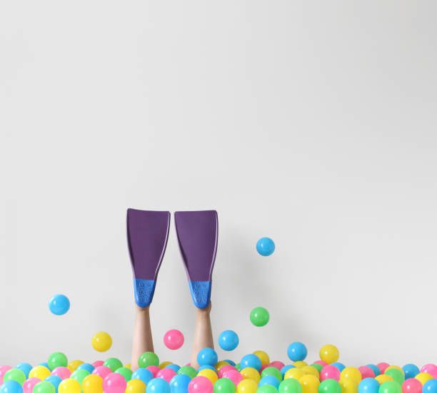 Woman wearing scuba fins diving into a conceptual ocean of plastic balls