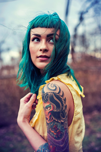 Portrait of young woman with blue hair and tattoos looking up over her shoulder. #tattoo #ink #portrait