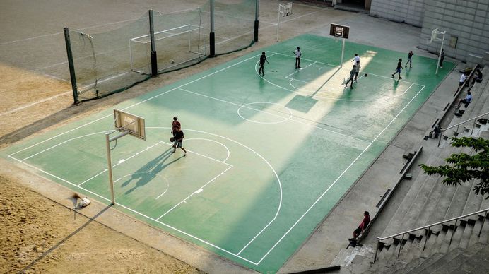 People playing basketball on a green basketball court with bleachers