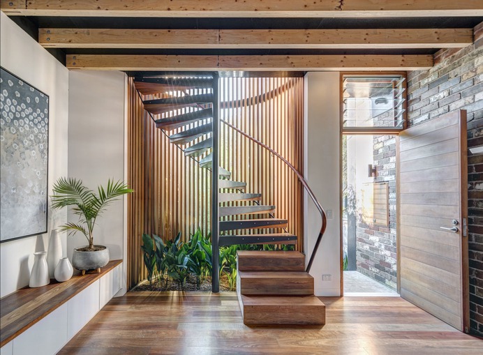 A cylindrical glass staircase with Western red cedar and painted steel mullions dominates the front of the house. The stair treads, along with the floor, are made of recycled spotted gum. Cedar spiral staircase.