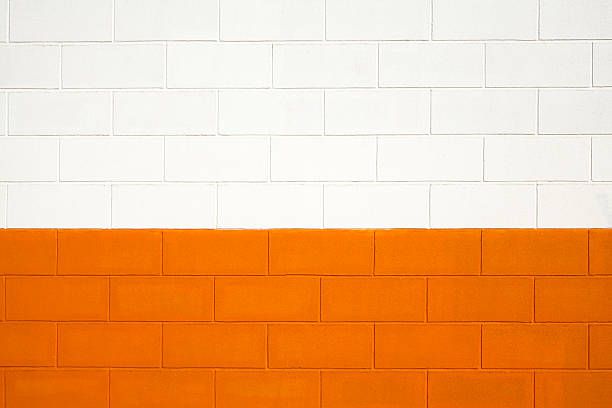 Brick wall painted white and orange, background full frame.