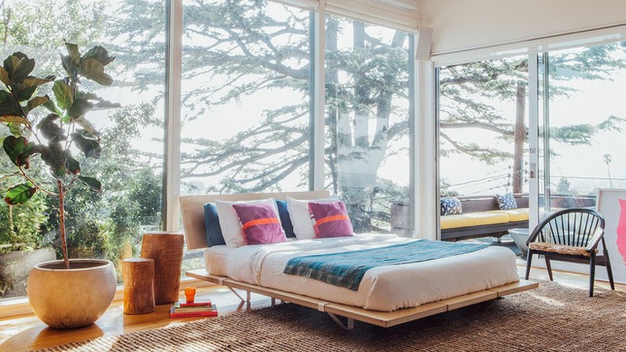 A vibrantly dressed mattress on the Queen size Floyd Platform Bed Frame with White steel supports and an attached Floyd Headboard