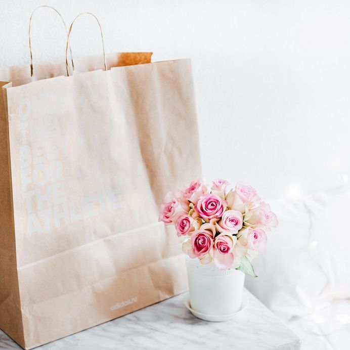 A cup of flowers next to a gift bag.