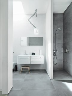 Bath Room and Ceiling Lighting The resident family shares one main bathroom, which is outfitted with Vipp's line of products: 982 bath furniture, a 906 faucet, and a 992 mirror. The shower sports a Raindance Connect showerhead by Hansgrohe, and there is a wall-mounted toilet by Villeroy & Boch. The Nomad light fixture is from Modular Lighting Instruments, and the floors are topped with ceramic tiles by LaFaenza.