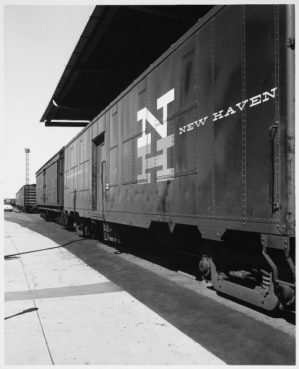 New Haven Railroad, NH Logo on Side, Parked train, Train on Diagonal into Distance at Rail Yard Over Hang, Cement and Paving next to Tracks #new #haven #herbert #matter