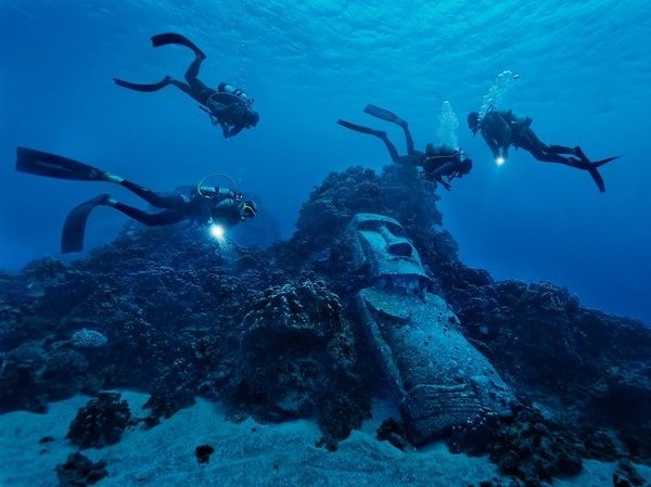 Picture of divers exploring a reef with fake moai off of Easter Island #ocean #water #divers #dive #calm #moai #blue