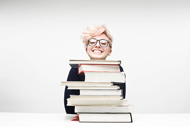 Happy Female Student Sitting Behind Pile of Textbooks