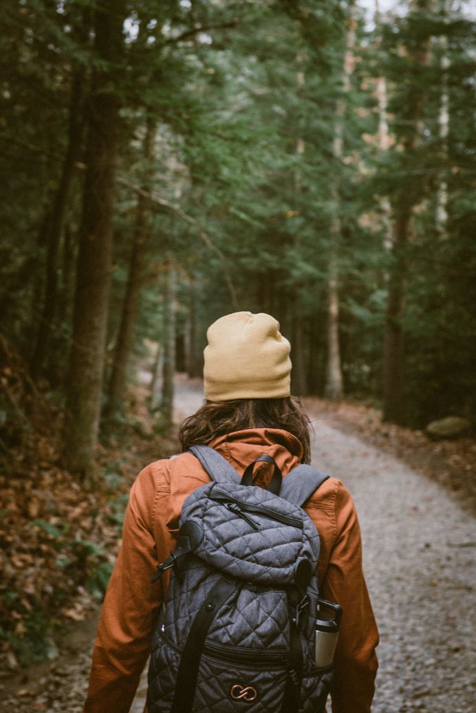 A person in a cap and backpack hikes down a trail at Lula Lake Land Trust